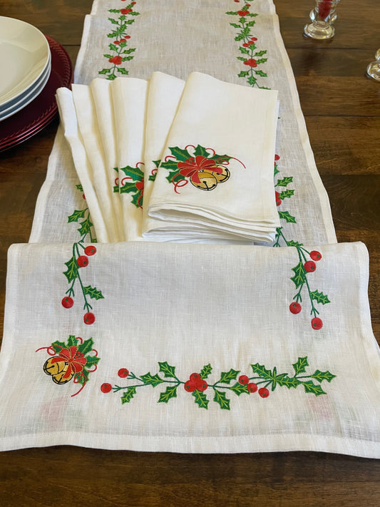 Elegant linen table runner featuring embroidered holly leaves and golden bells for Christmas dining
