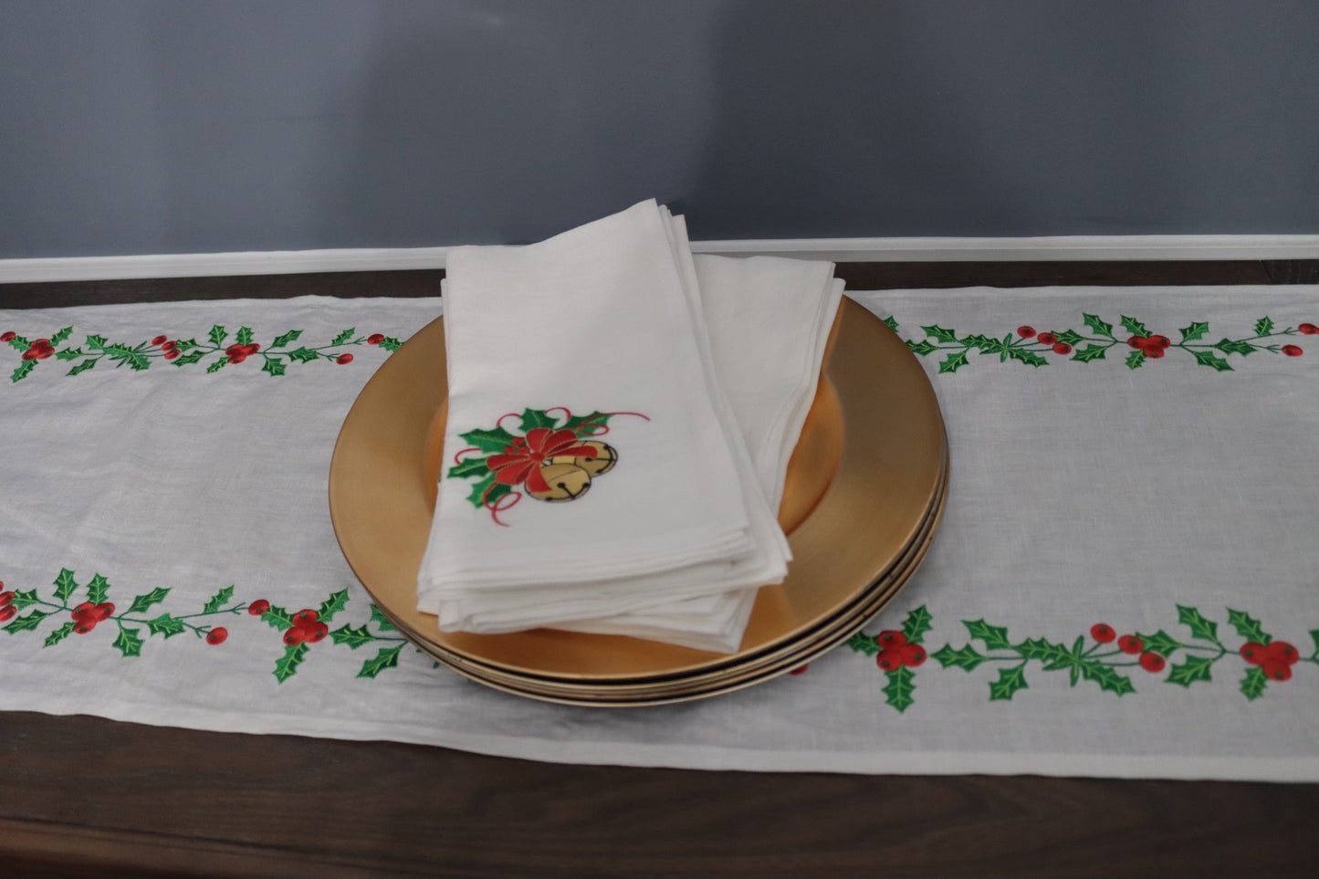 Elegant linen table runner featuring embroidered holly leaves and golden bells for Christmas dining