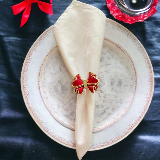 Featuring a napkin ring with an elegant red bow with gikd trim made of alloy on a whitte napkin.