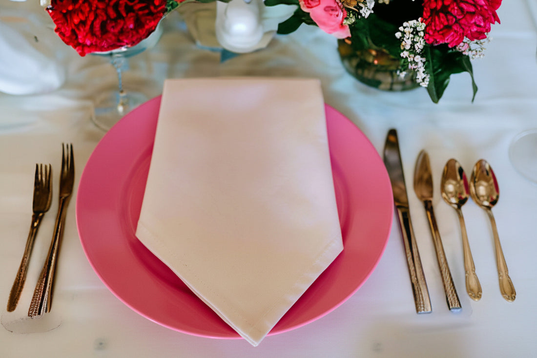 Romantic Valentine's Day table setting for two with red plates, white napkins, decorative napkin rings, and candlelight