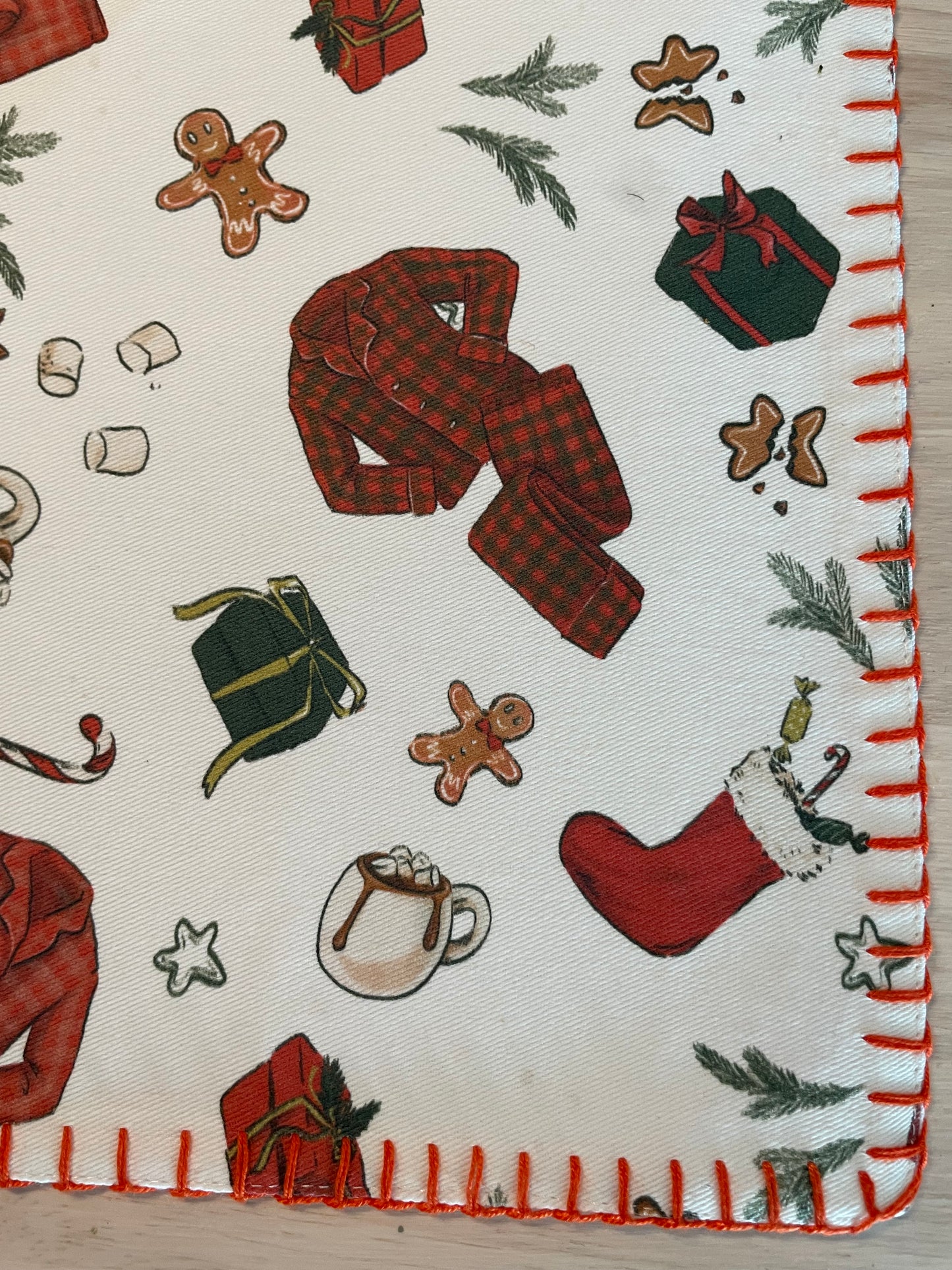 Fabric with Christmas-themed patterns including stockings, presents, and gingerbread men on a off-white background.
