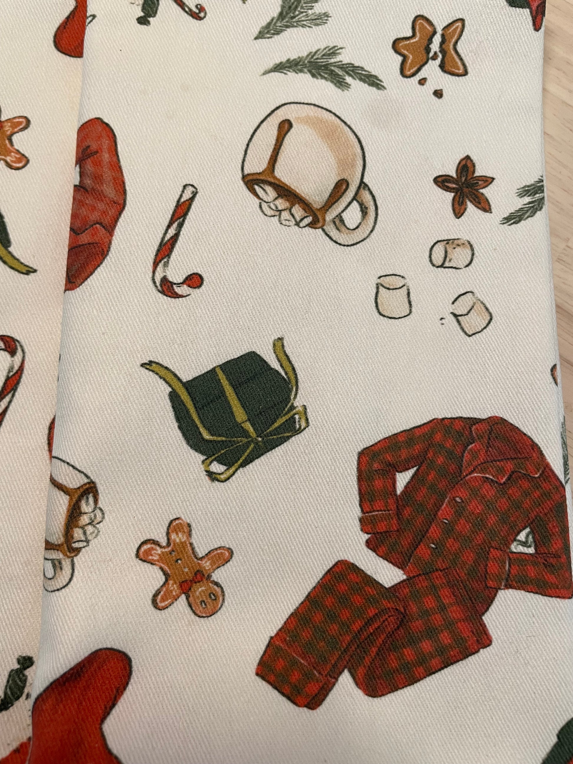 Cotton holiday napkins with Christmas morning print, showing pajamas, hot chocolate, cookies, stockings, and presents on a festive table.
